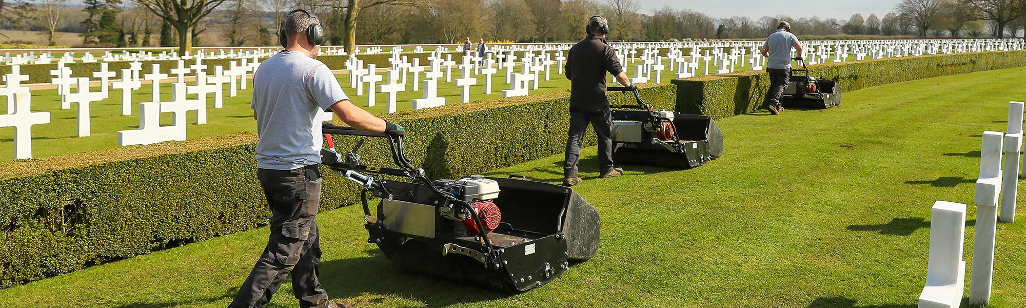 Large Allett cylinder mowers working across an open park area