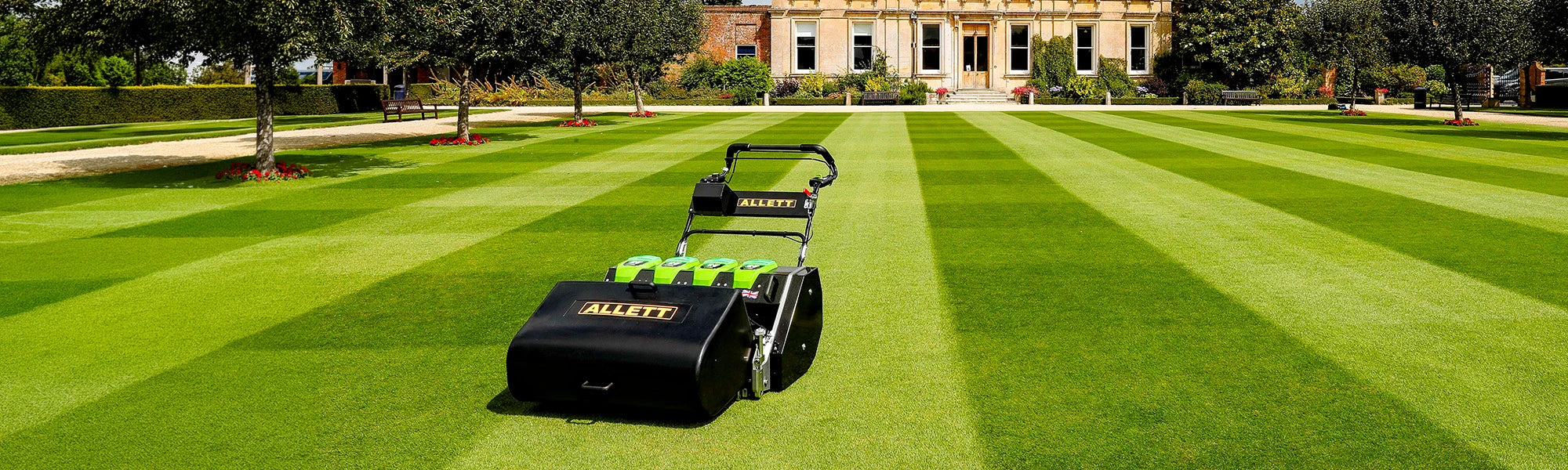 Compact Allett mowers cutting around flower beds and detailed park areas