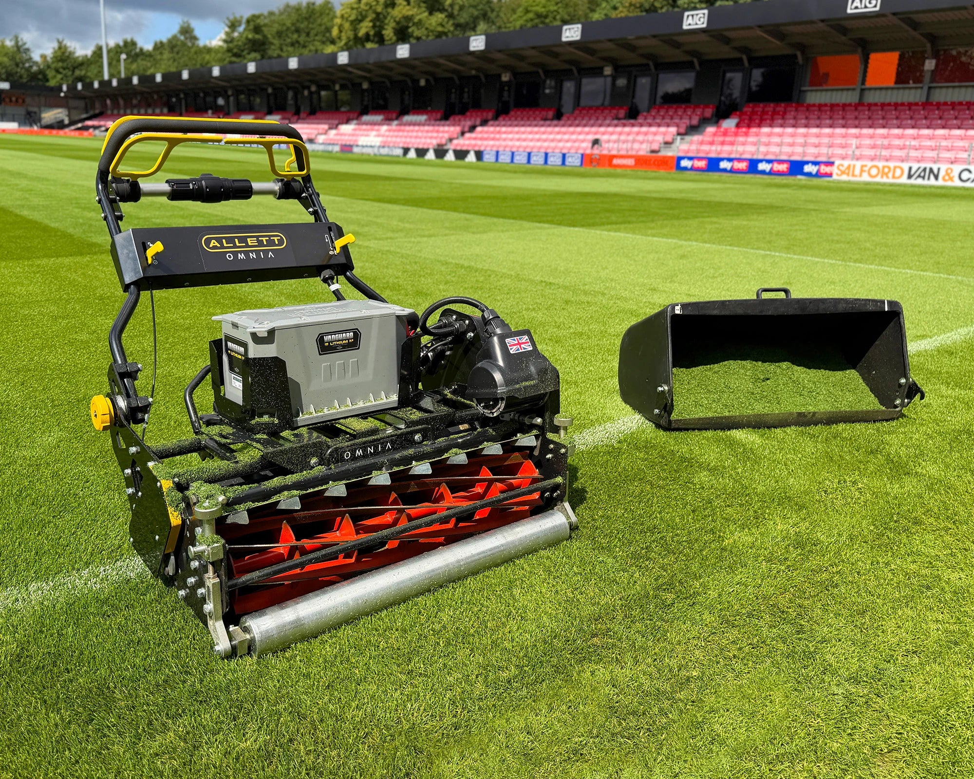 Allett OMNIA 34 at Salford City football club with a grassbox full of grass clippings on a fresh cut pitch.